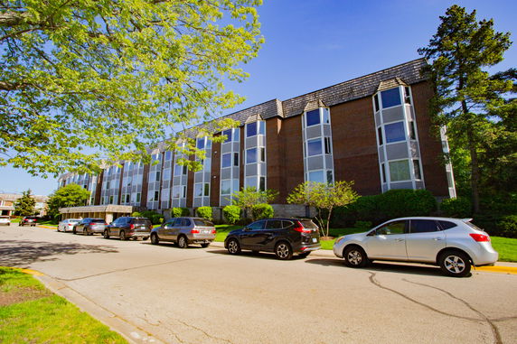 Front view of a multi-story building with large windows and a sloped roof.