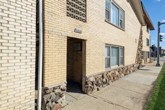 Front view of a multi-story brick building with a stone base and entrance.