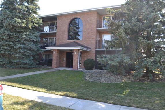 Front view of a three-story brick apartment building with balconies.