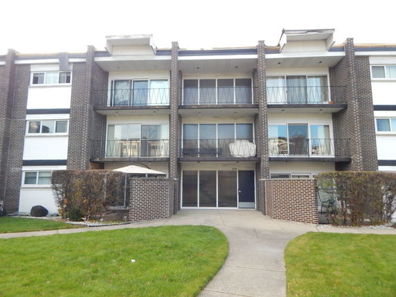 Front view of a multi-story apartment building with balconies.