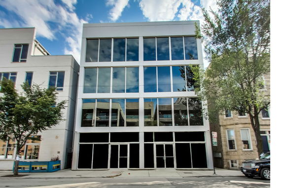 Front view of a modern three-story building with large reflective windows.