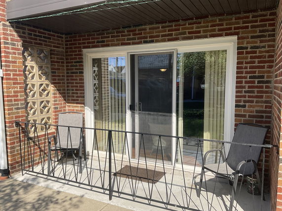 Front view of a brick house with a small balcony and sliding glass door.