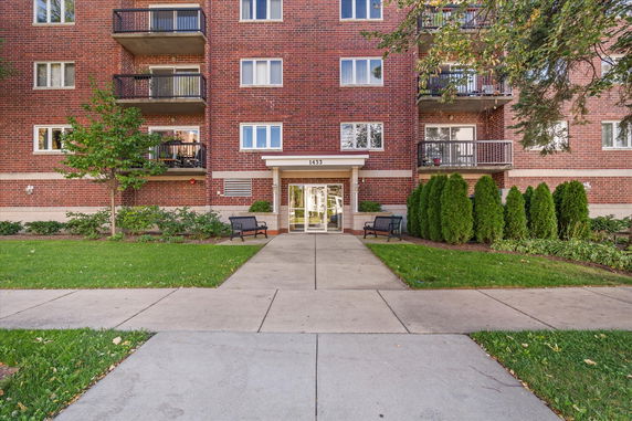 Front view of a multi-story brick apartment building with balconies.