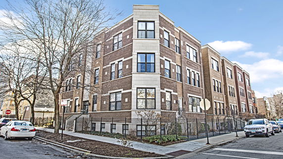 Front view of a multi-story brick apartment building on a street corner.