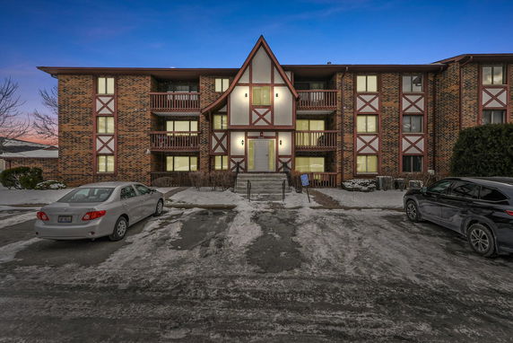 Front view of a multi-story building with a triangular roof and brick facade.