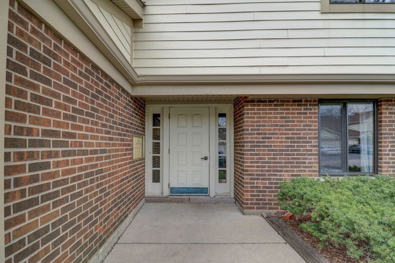 Front view of a brick exterior building with a white door and side windows.
