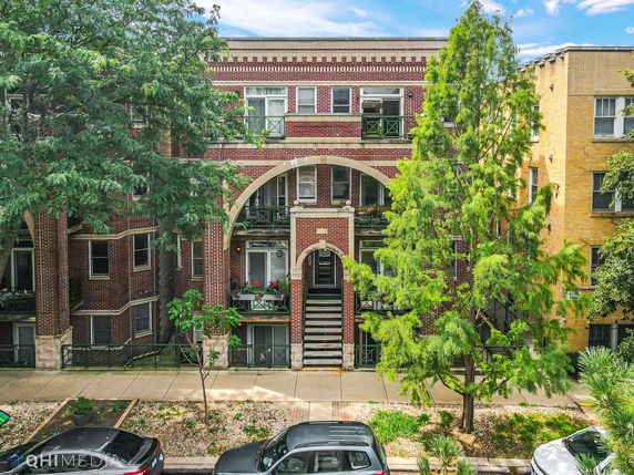 Front view of a multi-story brick building with arch details and balconies.