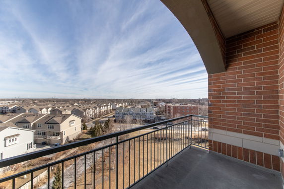 View of a neighborhood from a balcony with multiple residential buildings and clear sky.