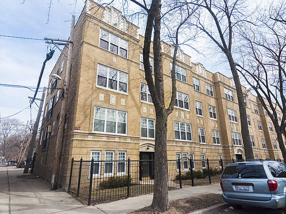 Front view of a multi-story brick apartment building with large windows.