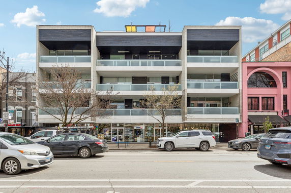 Front view of a multi-story building with balconies and a ground-floor storefront.