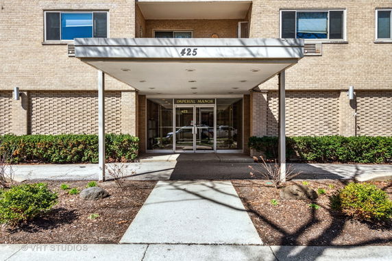 Front view of a building entrance with a covered walkway and brick exterior.