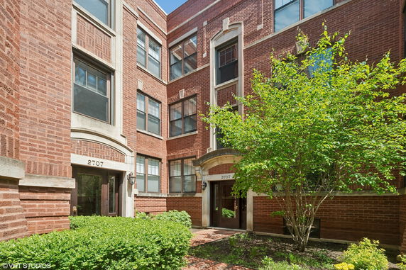 Front view of a brick multi-story residential building with multiple windows and entrances.