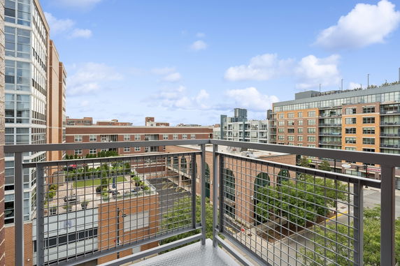 View from a balcony overlooking neighboring multi-story buildings and a courtyard.