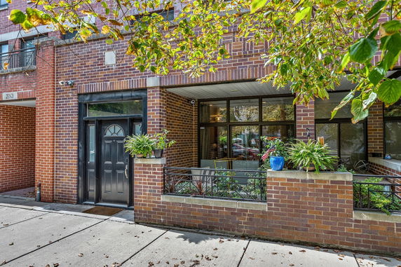 Front view of a brick building with large windows and plants.