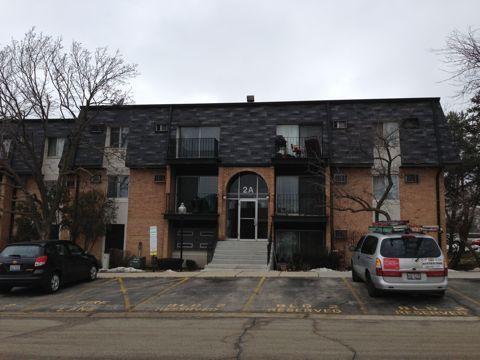 Front view of a three-story apartment building with a central staircase and a dark roof.