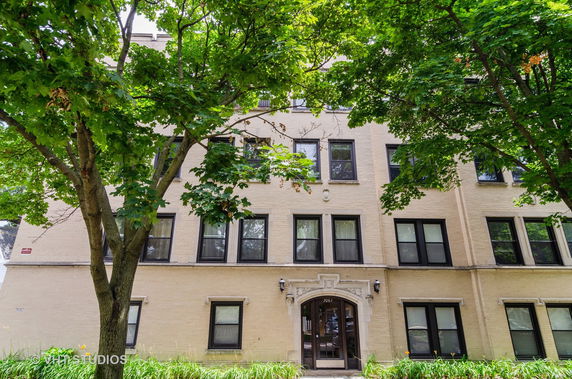 Front view of a multi-story residential building with large windows and an arched entrance.