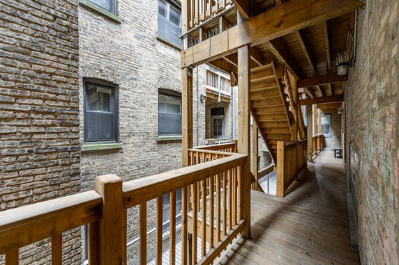 Exterior view of a brick building with wooden staircase and balcony.