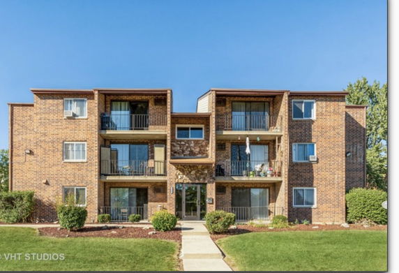 Front view of a three-story apartment building with brick exterior and balconies.