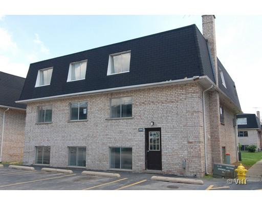 Front view of a multi-story building with brick exterior and dormer windows on the roof.