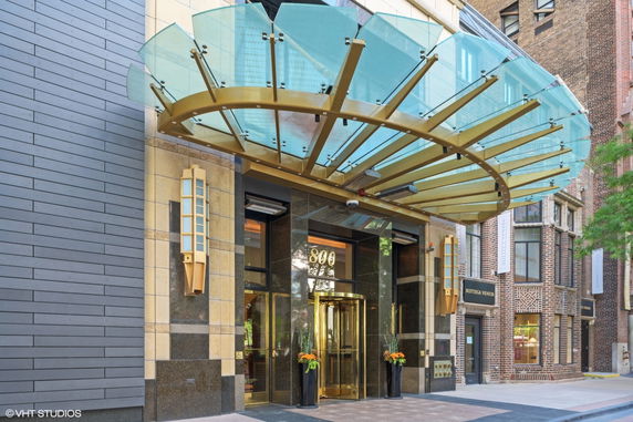 Front view of a building entrance with a glass canopy and revolving door.