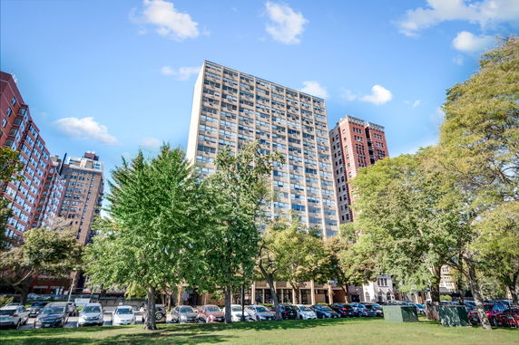 Front view of a multi-story building with a parking lot in front.