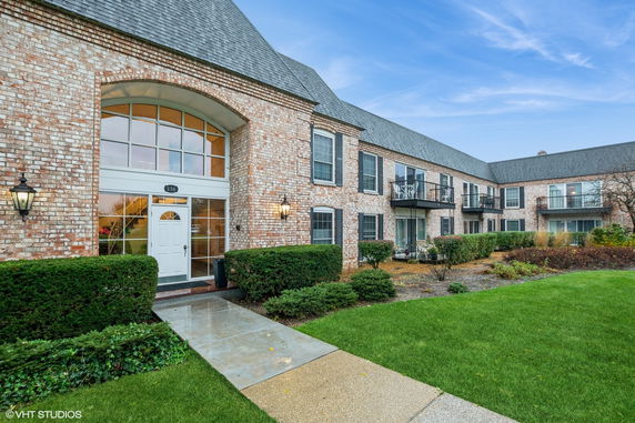 Front view of a brick residential building with multiple entryways and balconies.