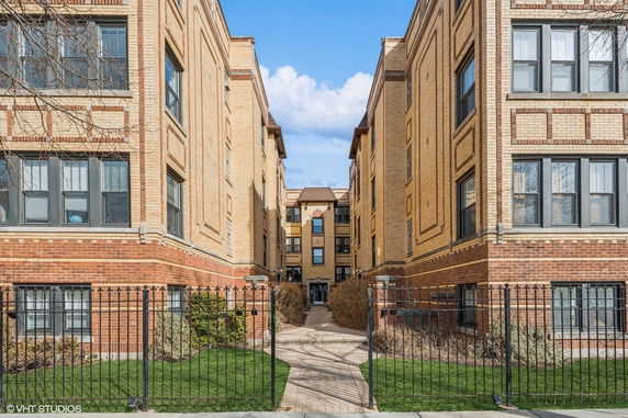 Front view of a multi-story brick building with a gated entrance.