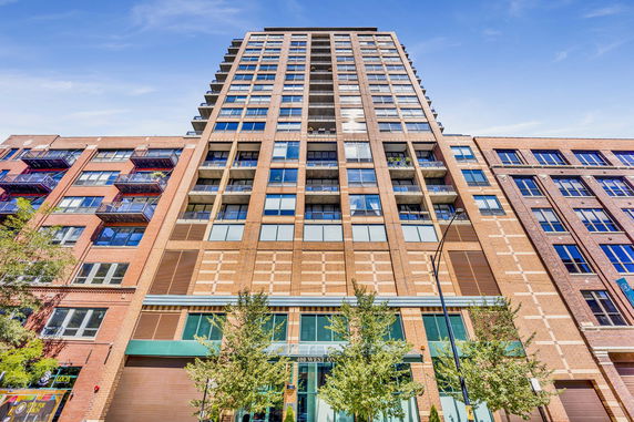 Front view of a multi-story brick building with balconies and large windows.