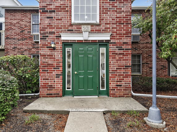 Front view of a brick building with a green door and windows on each side.