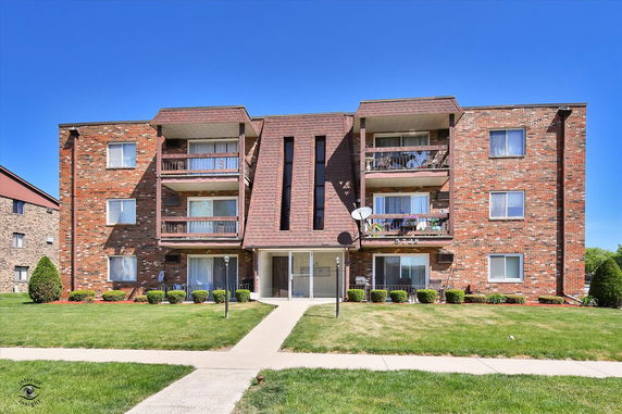 Front view of a multi-story brick apartment building with balconies.