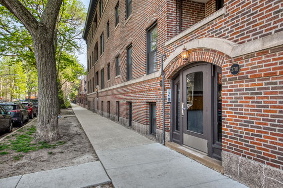 Front view of a brick multi-story apartment building with arched entrance.