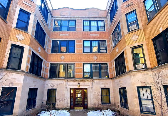 Front view of a multi-story brick building with multiple windows and a central entrance.