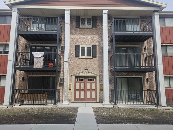 Front view of a three-story apartment building with balconies.