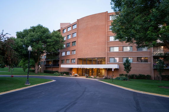 Front view of a multi-story brick building with a driveway and entrance canopy.