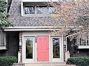 Front view of a house with a red door and large upper windows.