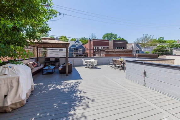 Rooftop with seating area and tables with views of neighboring houses.