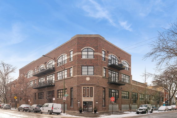 Front view of a three-story brick building with large windows and balconies.