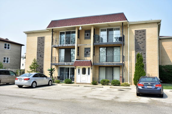 Front view of a three-story apartment building with a parking area.