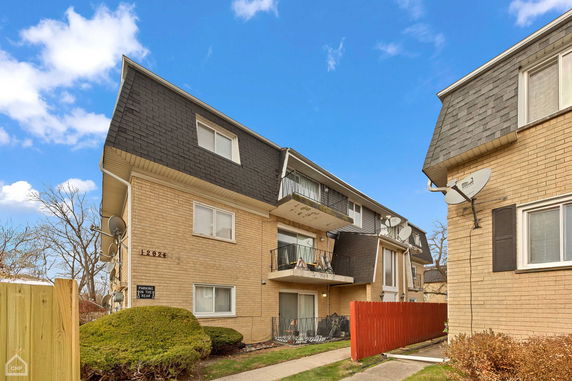 Front view of a multi-story building with balconies and satellite dishes.