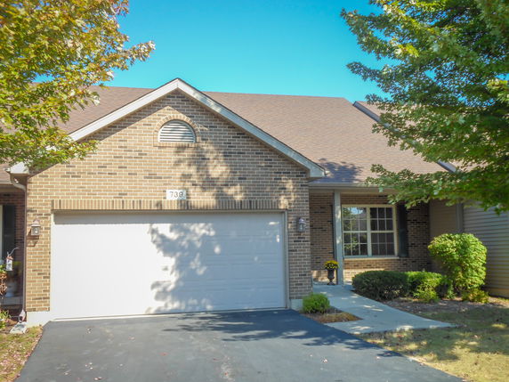 Front view of a single-story house with a brick facade and attached garage.