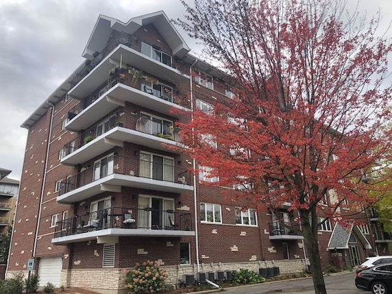 Front view of a multi-story brick apartment building with balconies.