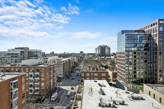 Panoramic view of urban buildings with a mix of modern and older structures under a blue sky.