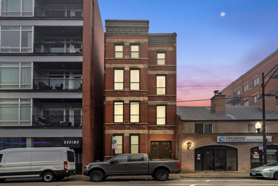 Front view of a multi-story brick building between two other structures.