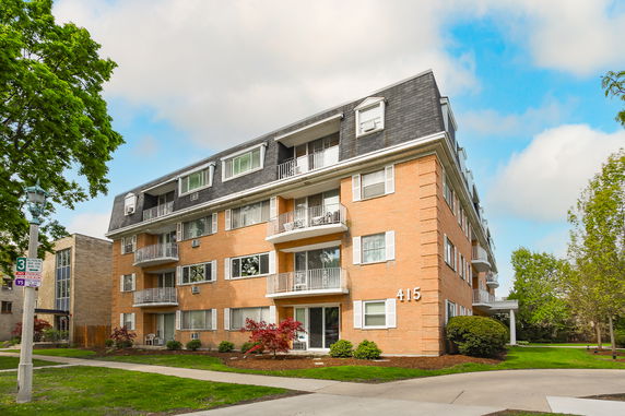 Front view of a multi-story brick apartment building with balconies.