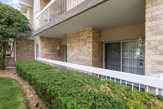Front view of a brick apartment building with balconies and greenery.