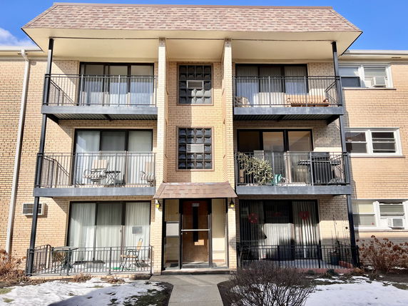 Front view of a three-story apartment building with balconies.