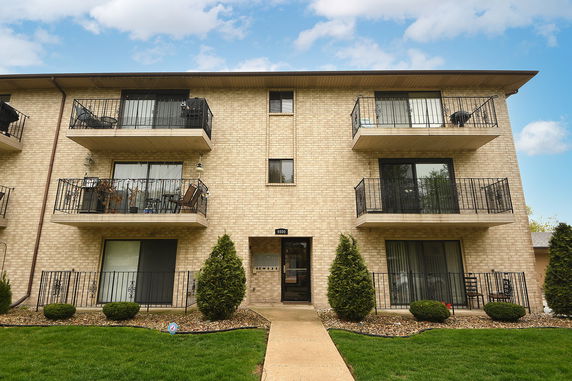 Front view of a multi-story apartment building with balconies and a central entrance.