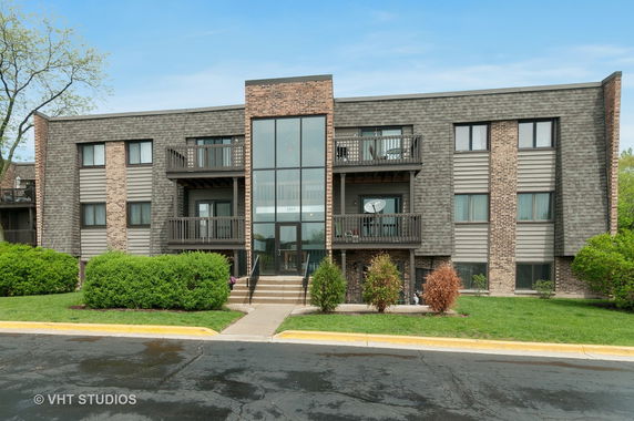 Front view of a three-story apartment building with balconies and a central glass entrance.