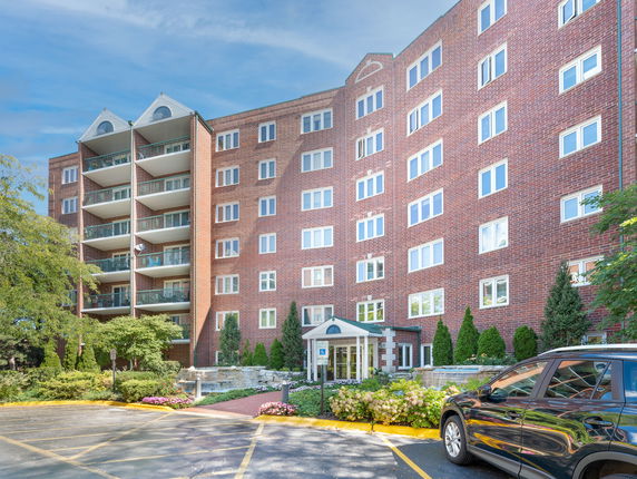 Front view of a multi-story brick building with balconies and multiple windows.
