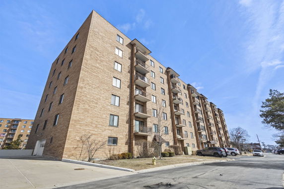 Front view of a multi-story brick apartment building with balconies.
